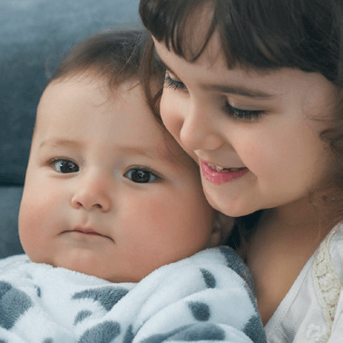 Smiling little girl holding baby