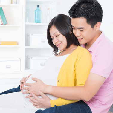 Couple smiling holding and looking at pregnant woman's belly