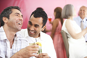 Two men having drinks and laughing at a party.