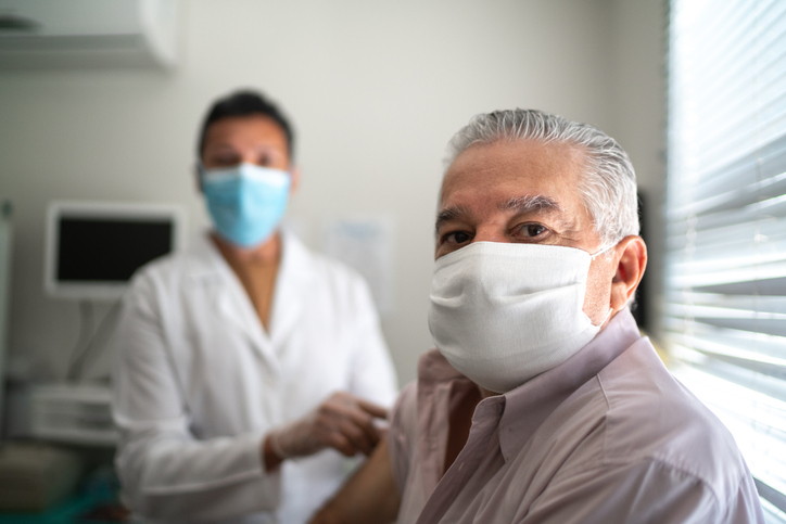 doctor giving shot to an older man