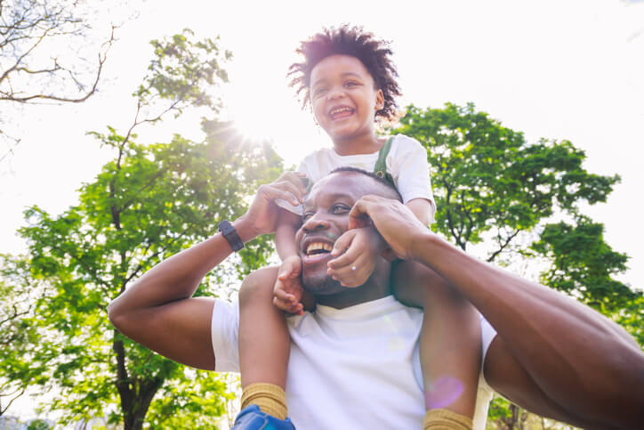african american father with a child on his shoulders