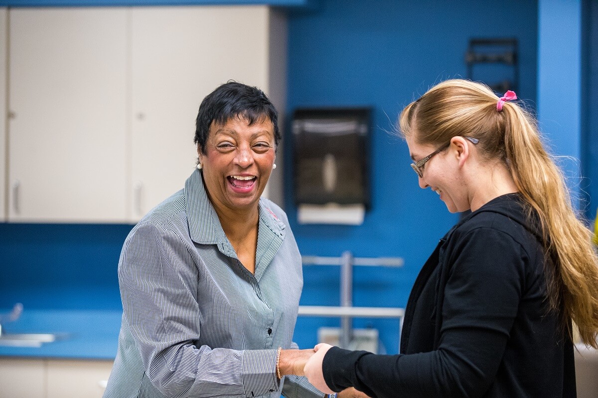 Female patient laughs while holding nurse's hand