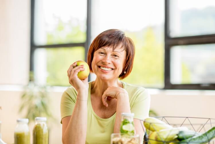 Woman holding apple and smiling