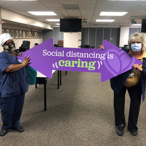 woman holding a social distancing sign