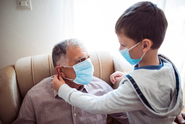 Kid putting mask on elderly man