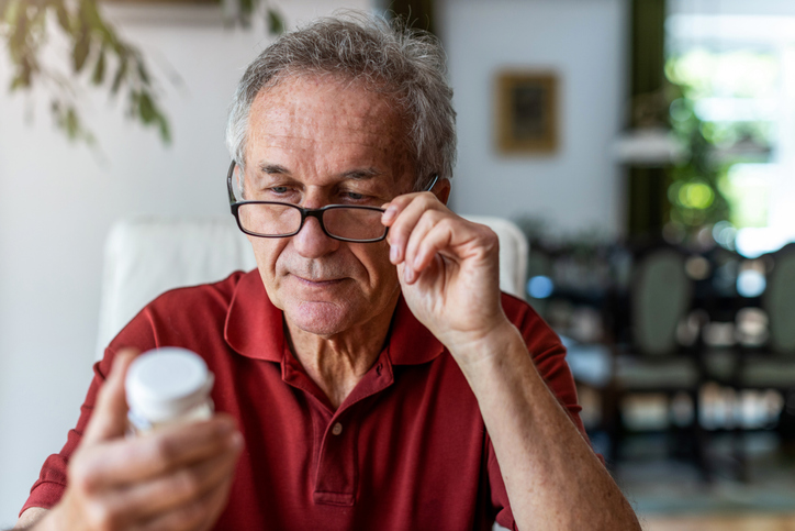 Senior man taking prescription medicine at home