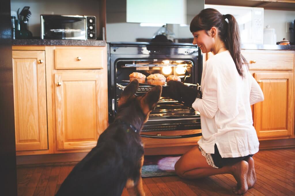 Woman baking with her dog beside her