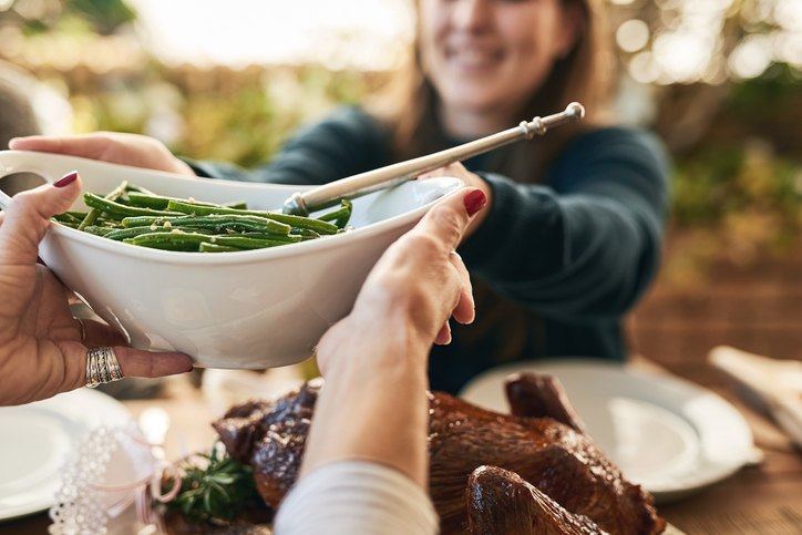 hands passing green beans to a woman