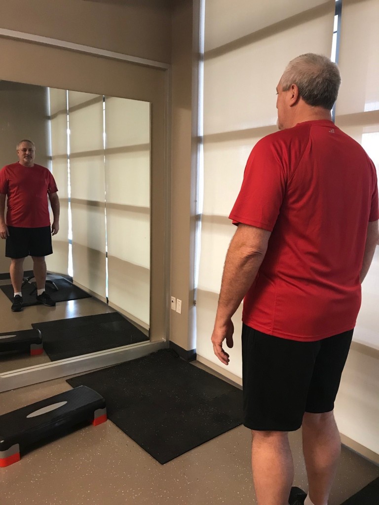 A man standing in front of the mirror in the gym