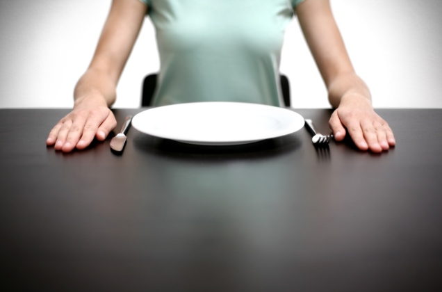 Woman sitting at table with plate and utensils