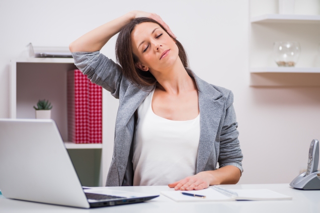 woman stretching neck at desk