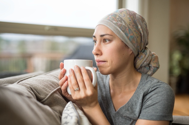 female cancer patient drinking tea and sitting on the coach