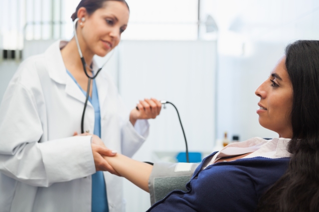 female physician checking female patient blood pressure