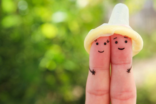 Faces drawn on fingers, with condom as "hat"