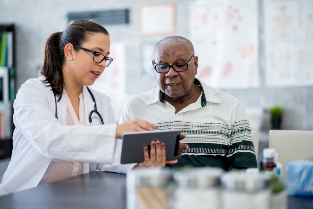 Female physician consulting male patient on tablet