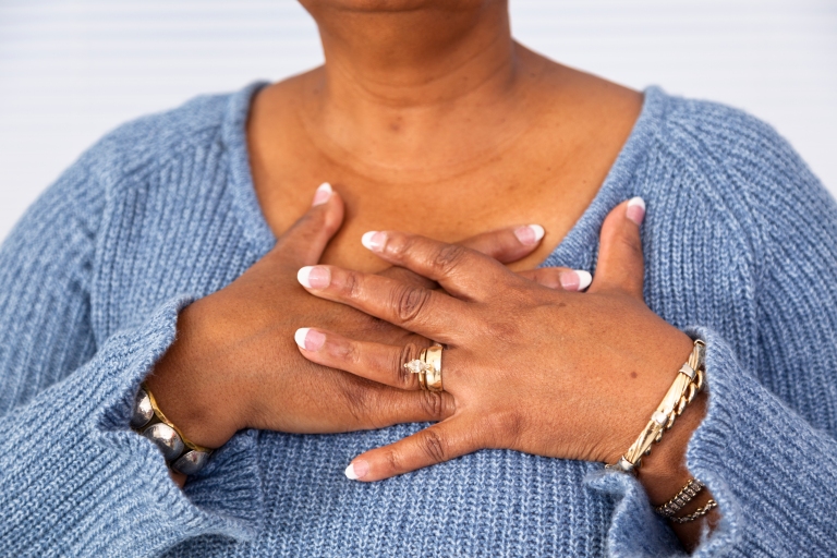 African American woman holding hands to heart