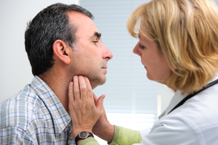 Female Physician examining man's throat