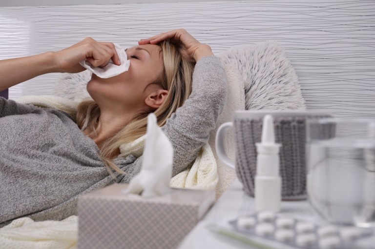 Woman laying down, blowing nose, sick