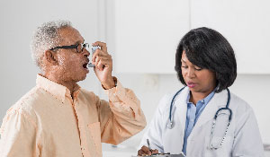 Man using inhaler beside doctor