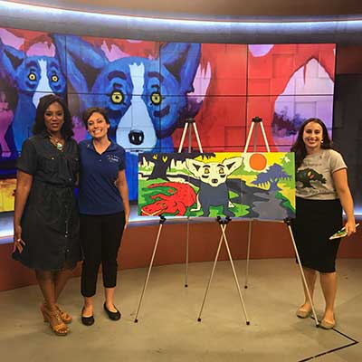 Paintfest - three women standing with art work